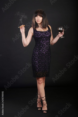 Trendy young brunette woman posing on a high chair, studio shot
