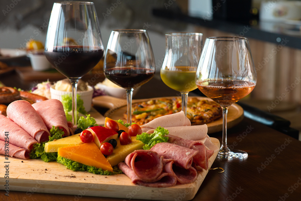 Antipasti platter with different meat and cheese products on wooden board