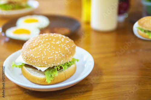Hamburger breakfast with blur fried eggs and seasoning background on wooden table - delicious fast food breakfast concept