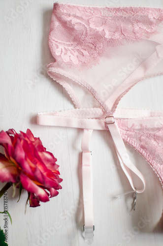 Sexy pink lingerie set with stocking suspender. Lace underwear on the white background with rose behind it.