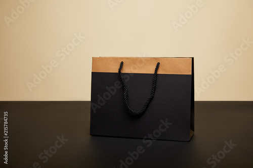 one black shopping bag on black table isolated on beige