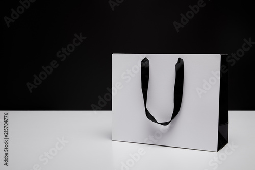 one white paper shopping bag on white table isolated on black