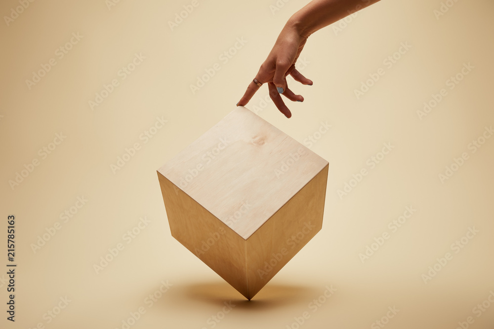 cropped image of woman touching wooden cube on beige