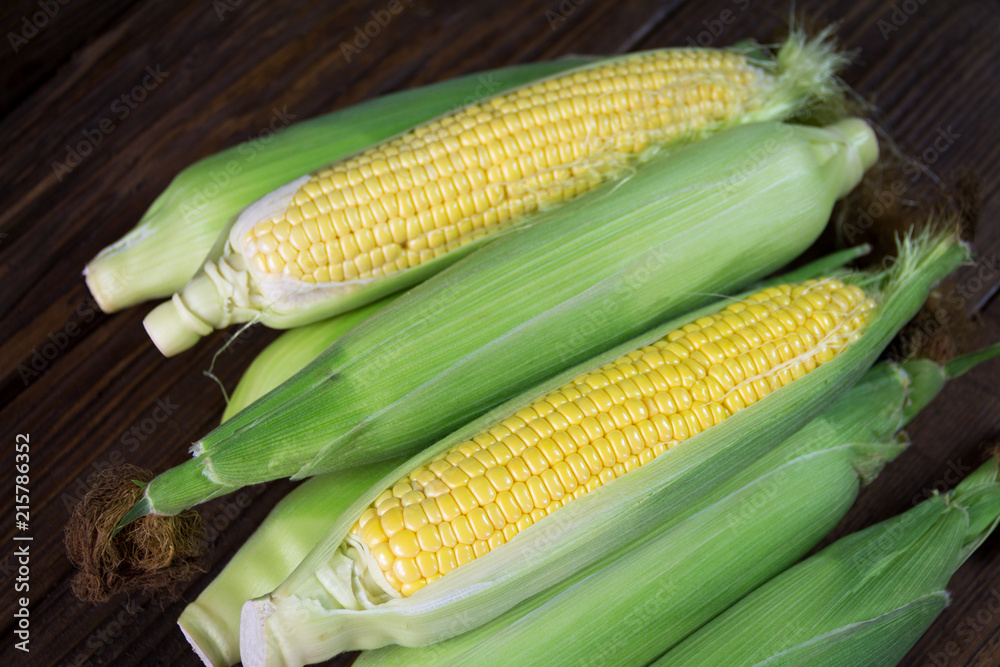 Freshly picked unpolished corn on a wooden background Freshly picked unpolished corn on a wooden background