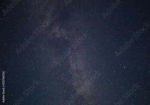 Night dark blue starry sky. Milky way galaxy with colorful bright shining stars, long exposure photograph, with grain.
