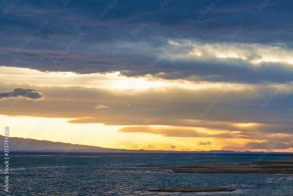 Scenic view of lake with grey mountains on horizon Scenic view of lake with grey mountains on horizon