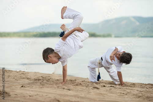 Training of two children on the beach: capoeira, sports