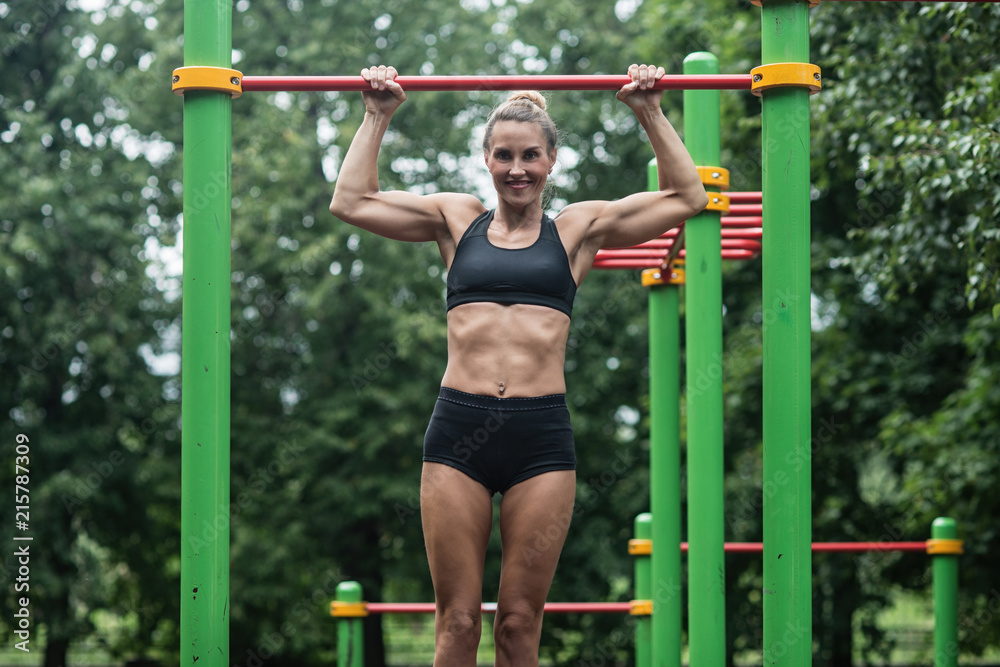 girl doing exercises on the horizontal bar. The woman is engaged in workout