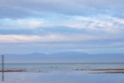Scenic view of lake with grey mountains on horizon   © photollurg