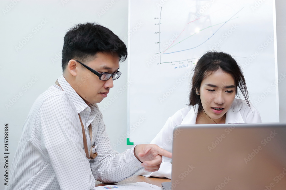 Two young Asian people brainstorming together in modern office. Teamwork business concept. Two young Asian people brainstorming together in modern office. Teamwork business concept.