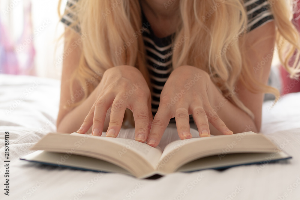 Woman sitting relaxed on the bead reading a book Woman sitting relaxed on the bead reading a book