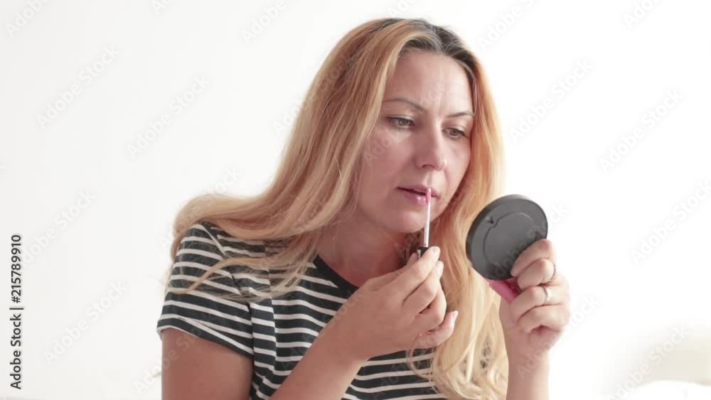Woman puttiing makeup on white background. Smiling woman prepares for a date Woman puttiing makeup on white background. Smiling woman prepares for a date