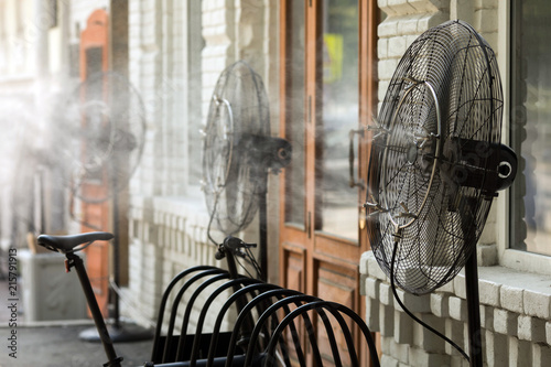 Contemporary system of fans with pulverizes spraying water with air and cooling air outdoors in hot summertime