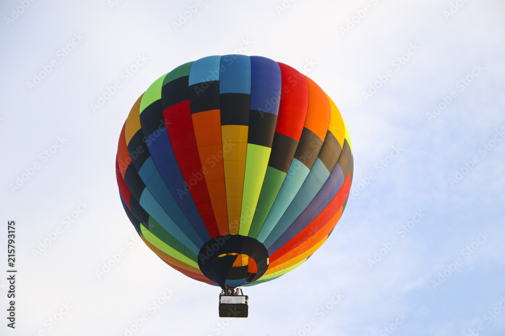 Fototapeta premium kolorowy balon na ogrzane powietrze przeciw błękitne niebo. w białych chmurach leci balon na ogrzane powietrze. piękne latanie balonem