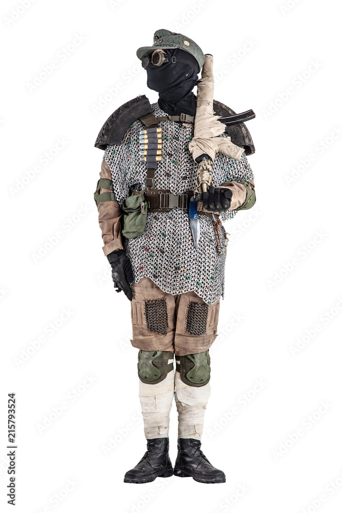 Post apocalyptic soldier in black mask and glasses, wool field cap and handmade armor from car tires and hauberk, standing at attention with submachine gun on shoulder, isolated on white studio shoot Post apocalyptic soldier in black mask and glasses, wool field cap and handmade armor from car tires and hauberk, standing at attention with submachine gun on shoulder, isolated on white studio shoot