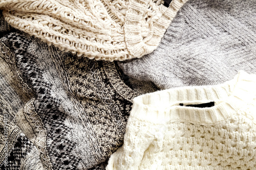 Bunch of knitted warm pastel color sweaters with different knitting patterns laid in messy pile, clearly visible texture. Stylish fall / winter season knitwear clothing. Close up, copy space for text.