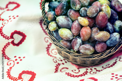 Ripe plums in wicker basket shortly after rain in bright sunlight photo