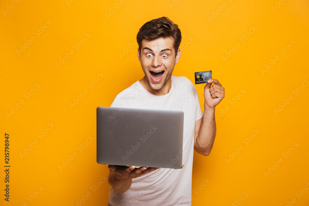 Portrait of an excited young man holding laptop computer Portrait of an excited young man holding laptop computer
