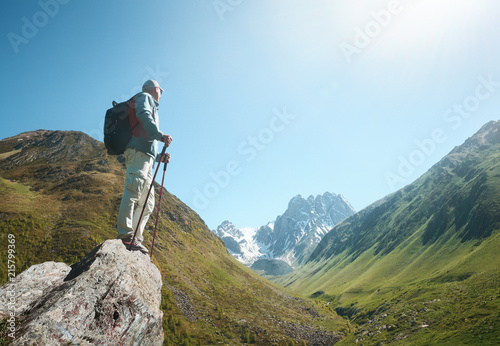 traveller with Backpack and trekking sticks look view of the Chauhi mountain range in Georgia (country).