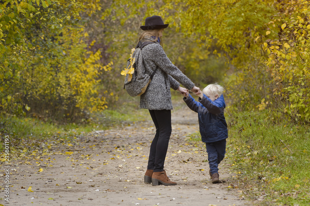 Fototapeta premium Mom and son are playing in the autumn forest.
