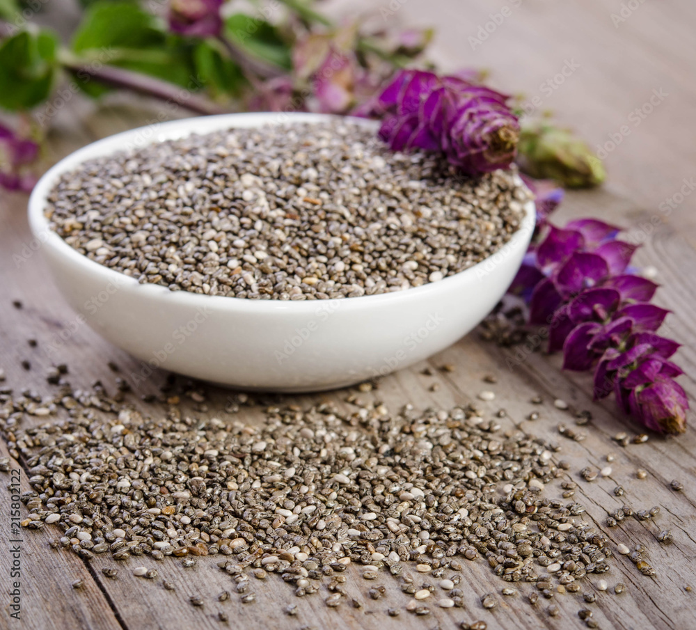 Chia seed healthy superfood in bowl with flower over wooden table Chia seed healthy superfood in bowl with flower over wooden table