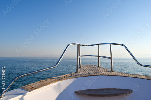 View from yacht over the ocean, horizon in background, blue sky