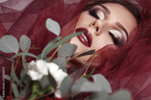 Portrait of young woman with fashionable makeup and eucalyptus bouquet photo