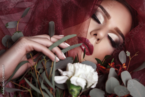 Portrait of young woman with fashionable makeup and eucalyptus bouquet photo
