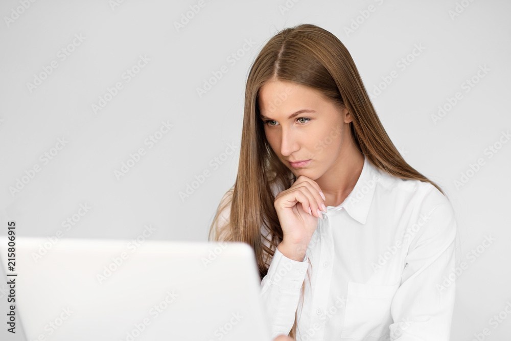 Young beautiful woman is working on a laptop in the office on a white background. Young beautiful woman is working on a laptop in the office on a white background.