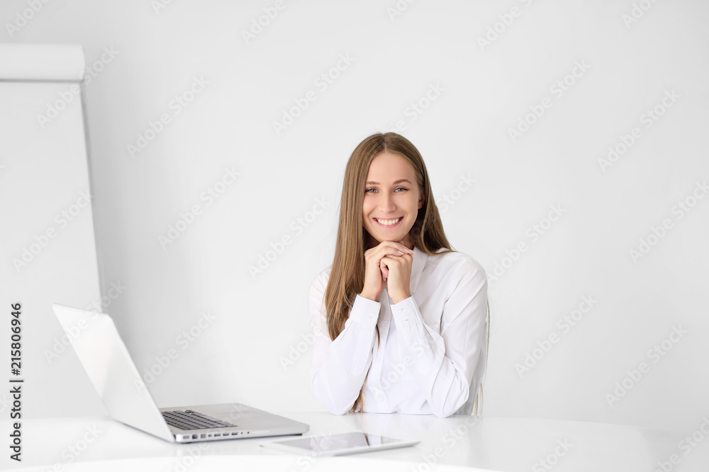 Young beautiful woman is working on a laptop in the office on a white background. Young beautiful woman is working on a laptop in the office on a white background.