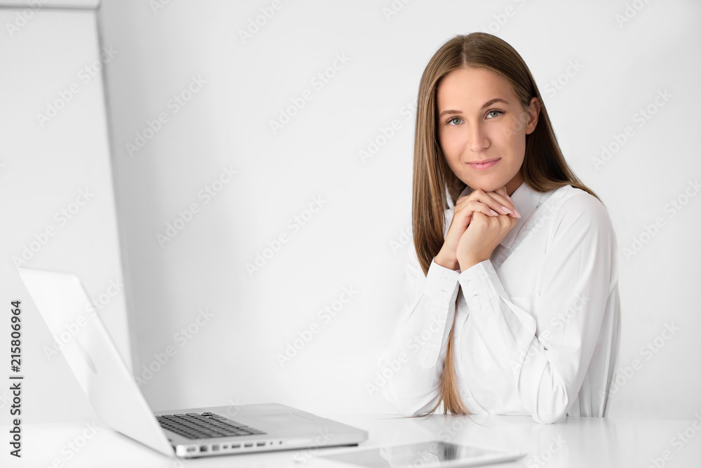 Young beautiful woman is working on a laptop in the office on a white background. Young beautiful woman is working on a laptop in the office on a white background.