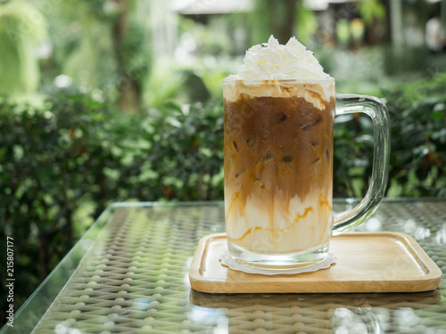 One cold coffee with whip cream in glass on mirror in the garden.