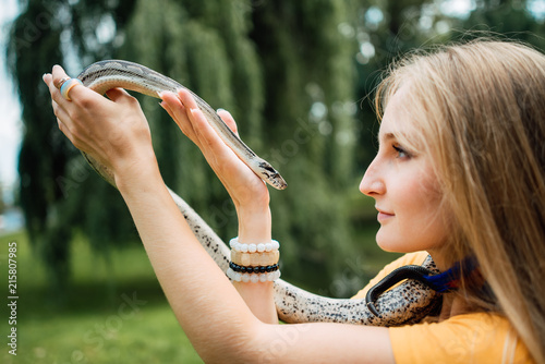 beautiful blonde girl is holding a snake in her hands. Contact the zoo.