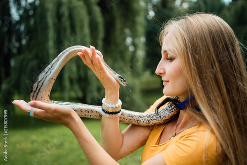beautiful blonde girl is holding a snake in her hands. Contact the zoo.