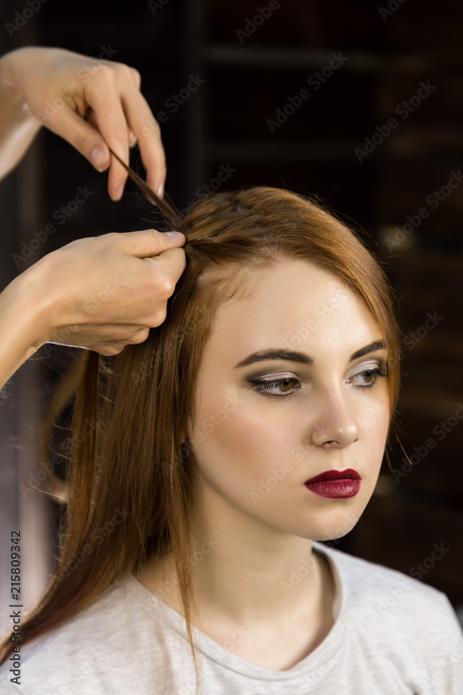 Naklejka premium Hairdresser does hairstyle for young woman to weave braids. Concept beauty and wedding
