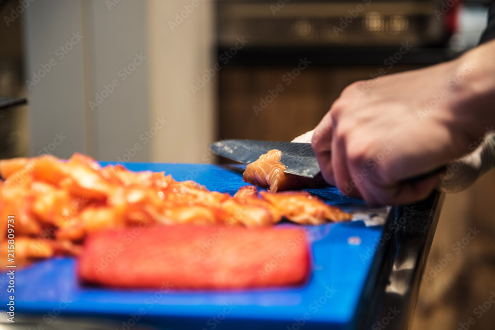 Chef cutting salmon fish on a blue plastic table