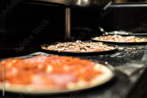Close-up of three pizza in the making ready for oven