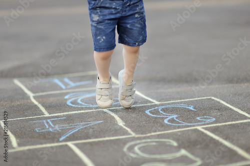 Closeup of little boy s legs and hopscotch drawn on asphalt