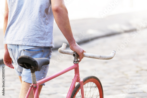 Cropped picture of handsome young caucasian man early morning with bicycle walking outdoors