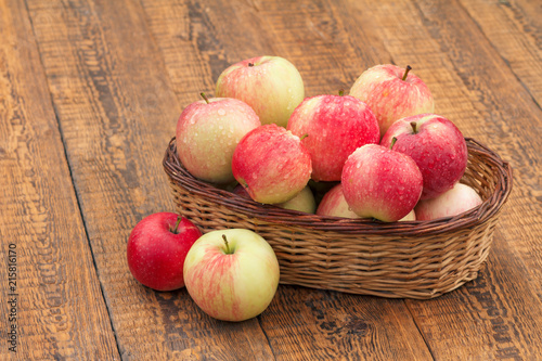 Red apples in wicker basket on wooden boards