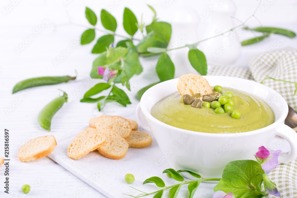 Green pea soup puree with croutons in black bowl. On white background Green pea soup puree with croutons in black bowl. On white background