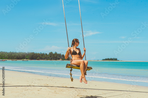 Swinging sexy girl at the beach n front of the tropical sea