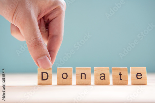 Man hand arranging wood with text Donate on blue background.