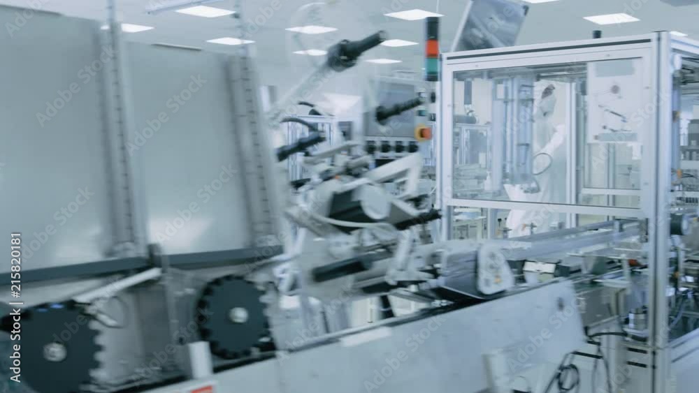 Gliding Shot through Sterile High Precision Manufacturing Laboratory where Scientists in Protective Coverall's Use Computers and Microscopes, doing Pharmaceutics. Gliding Shot through Sterile High Precision Manufacturing Laboratory where Scientists in Protective Coverall's Use Computers and Microscopes, doing Pharmaceutics.