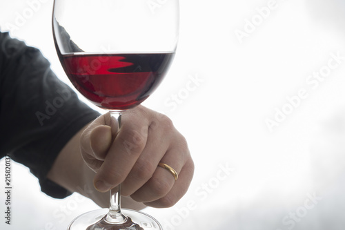 hand holding wineglass with red wine
