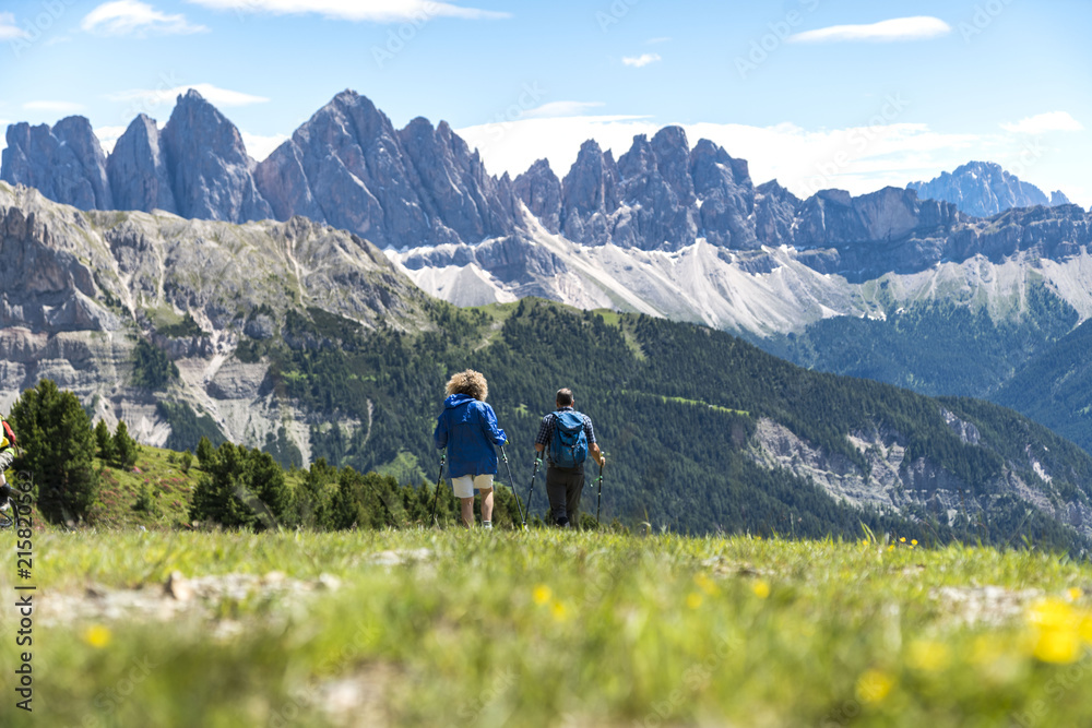 Two hikers walking to the geisler mountains in the italian dolomites