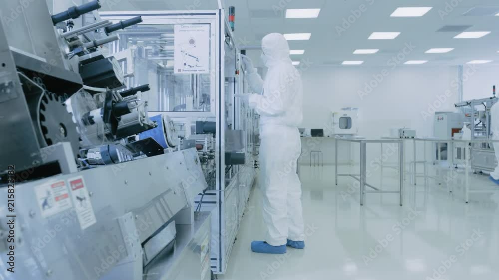 In the Laboratory Scientist Wearing Sterile Protective Coverall Set's up / Programs Modern Industrial 3D Printer, High Precision Manufacture of Semiconductors under Process.