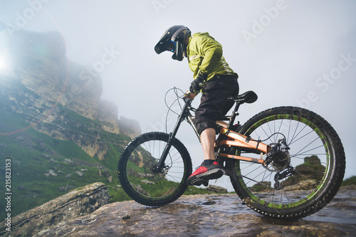 Fototapeta Naklejka Na Ścianę i Meble -  Portrait of a man aged on a mountain bike in the mountains in cloudy weather. Mountain bike concept