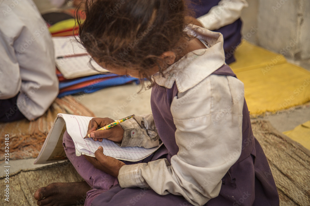 Poor Indian village school girl sitting on floor and doing her school  assignment. Stock Photo | Adobe Stock