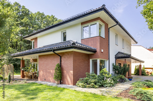 Cuadro en lienzo Red brick house with terrace and green grass and trees during summer